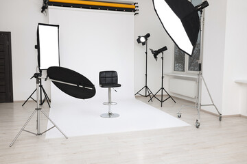 Interior of modern photo studio with bar stool and professional lighting equipment