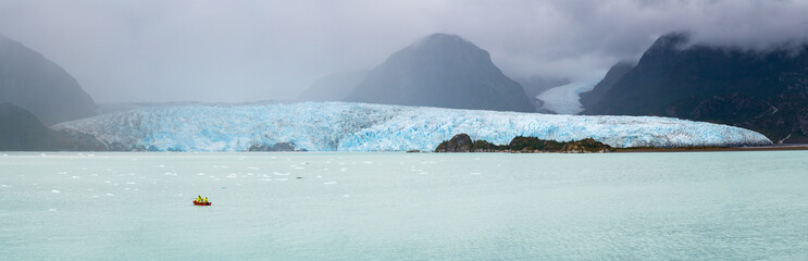 Panorama with crew in small power boat collecting iceberg by Amalia Glacier in Patagonia