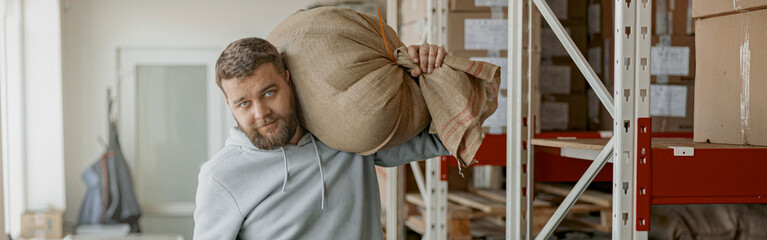 Male warehouse worker carries a bag of coffee beans ready for sale