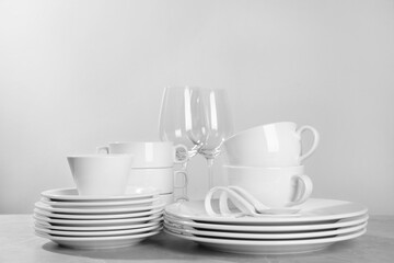 Fototapeta premium Set of clean dishware and glasses on grey table against light background