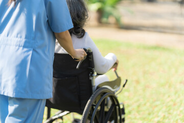 Obraz premium Young asian care helper with asia elderly woman on wheelchair relax together park outdoors to help and encourage and rest your mind with green nature.