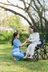 Young asian care helper with asia elderly woman on wheelchair relax together park outdoors to help and encourage and rest your mind with green nature. hold hands to encourage
