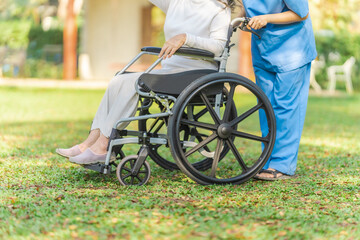 Obraz premium Young asian care helper with asia elderly woman on wheelchair relax together park outdoors to help and encourage and rest your mind with green nature.