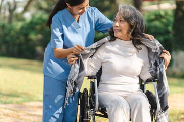 Obraz premium Young asian care helper with asia elderly woman on wheelchair relax together park outdoors to help and encourage and rest your mind with green nature.