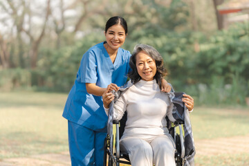 Young asian care helper with asia elderly woman on wheelchair relax together park outdoors to help and encourage and rest your mind with green nature.