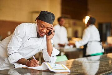 Young African chef on the phone in the kitchen at night