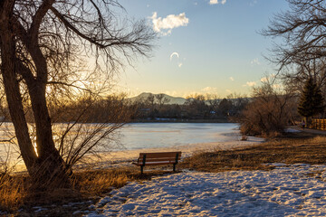 Kendrick Lake Park in Denver, Colorado. Iced lake at sunset with a bench on the shore