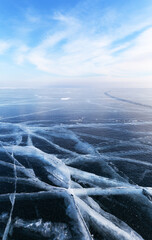 Picturesque winter landscape of frozen Baikal Lake on cold sunny February day. Beautiful natural background of endless icy desert with blue ice with white crack patterns. Winter travel and outdoors