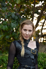 Close up portrait of beautiful female model with blonde plait, wearing black leather catsuit,...