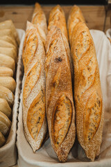 High angle view of many fresh handmade baguette breads on a rustic basket in a bakery