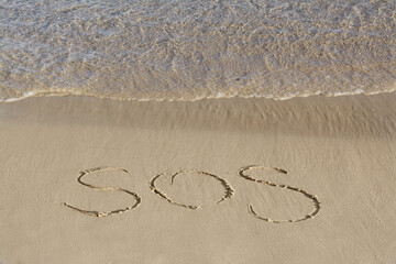 SOS message written on sand near sea