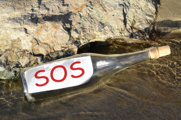 Glass bottle with SOS message near sea rock