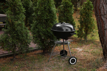 New barbecue grill near green trees in garden