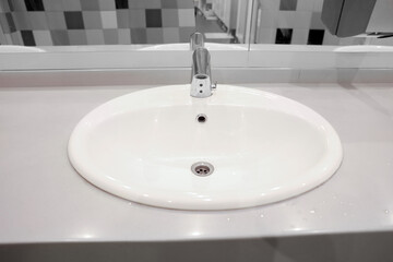 Clean ceramic sink near tiled wall in public toilet