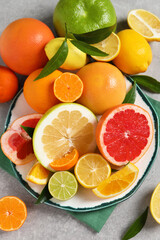 Different citrus fruits with fresh leaves on light grey table, flat lay