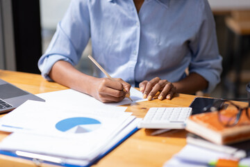 Accountant Young african businesswoman in afro hairstyle Using Calculator For documents Accounting financial sitting at computer in workplace office 