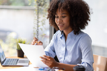 Accountant Young african businesswoman in afro hairstyle Using Calculator For documents Accounting financial sitting at computer in workplace office 