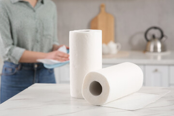 Woman wiping plate with paper towel in kitchen, selective focus