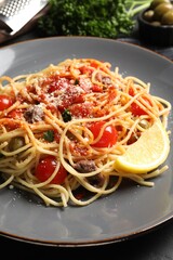 Delicious pasta with anchovies, tomatoes and parmesan cheese on table, closeup