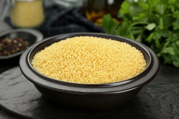 Bowl of raw couscous on grey table, closeup