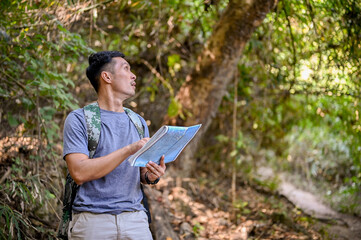 Active fit Asian male trekker or traveler with a backpack looking at the trekking route on the map