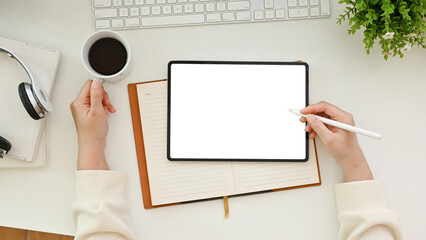 Top view, A female using digital tablet and sipping coffee at her minimal white office desk.