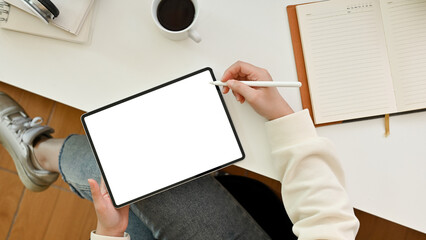 A female graphic designer designing her graphic artwork on digital tablet at her desk, top view