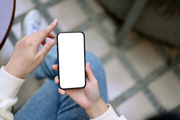 Top view of a woman sits at the backyard and uses her smartphone. phone white screen mockup