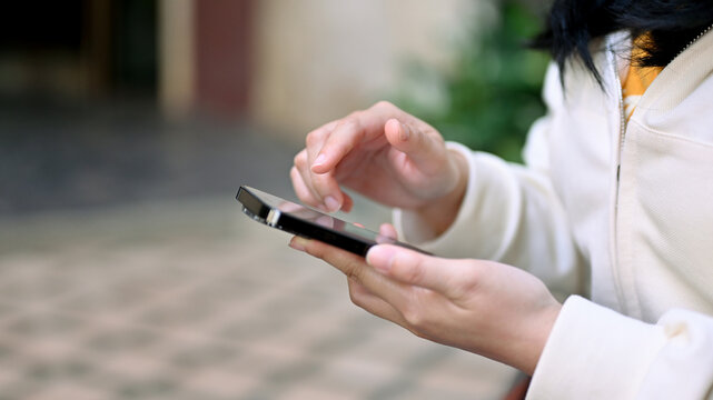 Close-up side view image of an Asian woman in casual clothes using her smartphone