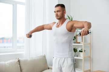Fototapeta na wymiar Man sportsman training at home with dumbbells, exercises for arms and back muscles, strong body and correct posture, the concept of health and beauty.