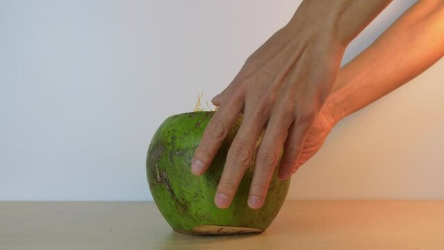 Close-up of a person leaving on the table in slow motion a cut green coconut with a straw ready to drink