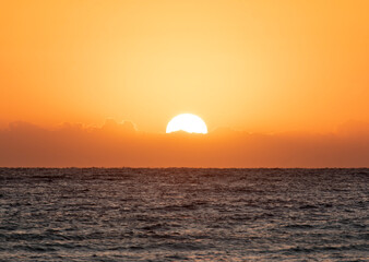 Sun behind wall cloud over the ocean horizon