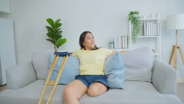 Asian young amputee leg woman lying down on comfort sofa in living room