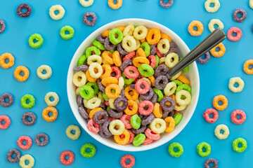 Colored breakfast cereal in a bowl on a blue background, flat lay, children's healthy breakfast,...