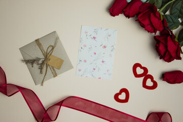 Valentine concept with vintage card, red roses and ribbon over the brown paper.