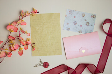 Letter concept with brown paper, envelope, flower and ribbon over the brown paper.