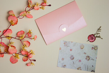 Letter concept with pink envelope and flowers over the brown letter.