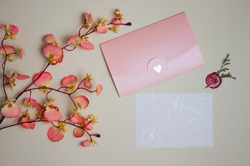 Letter concept with white paper, pink envelope and flowers over the brown background. 