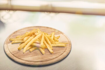 Freshly cooked tasty French fries on wooden board