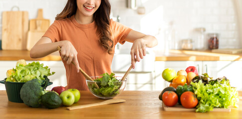 Portrait of beauty body slim healthy asian woman having fun cooking and preparing cooking vegan food healthy eat with fresh vegetable salad in kitchen at home.Diet concept.Fitness and healthy food