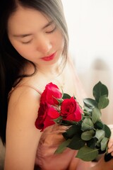 woman in pajamas colored rose gold With a red rose on the bed resting in the morning, Background concept, closeup flower.