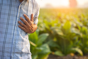 injuries or Illnesses, that can happen to farmers while working. Man is using his hand to cover over left chest because of hurt,  pain or feeling ill