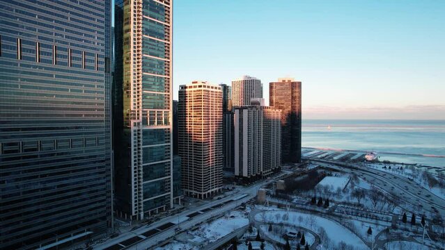 desceding aerial - Lake Michigan and part of chicago buildings with Lakeshore drive in view, aerial at the sunset