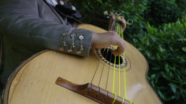 Mariachi playing guitar in slowmotion. Mexican man playing songs at an event.
