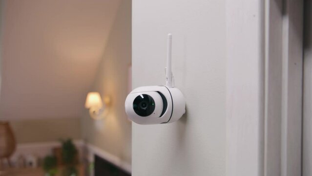 Close up shot of installed security camera on wall in modern apartment. CCTV camera with microphone and motion sensor. Concept of tracking system, surveillance and personal privacy. Dolly zoom.