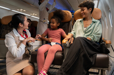 Airplane flight attendant providing service to kid and mother passengers on board.