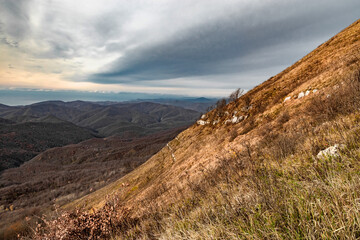 Dry grass on the slope of a high mountain. Landscape of a mountain range on an autumn morning. Mountain landscape with beautiful Caucasian nature. Panoramic view of the Caucasus mountains. 
