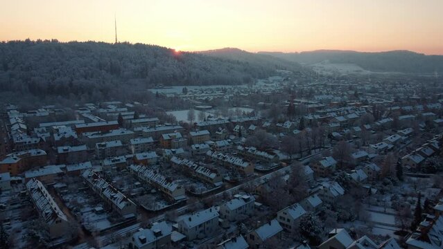 Aerial view of snow covered houses of Winterthur, flying towards the setting sun on a beautiful winter day. Switzerland, Canton, Zurich