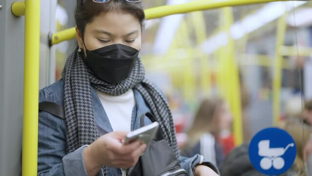 asian traveller adult woman wearing protective face mask during use bus shuttle public transportation in downtown city Europe,asia female traveller standing waiting for her next stop in Europe trip