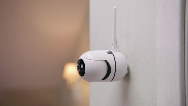 Close up shot of installed security camera on wall in modern apartment. CCTV camera with microphone and green indicator. Concept of monitoring system, surveillance and personal privacy. Dolly zoom.
